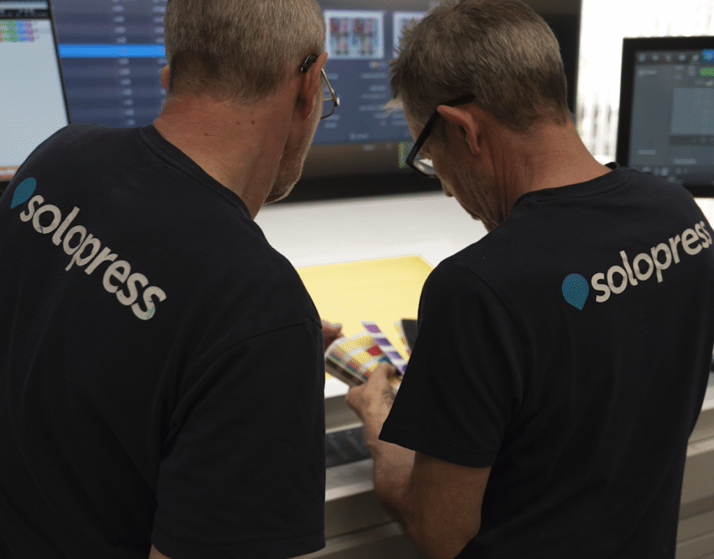 Two Solopress employees looking at a color swatch book at the press